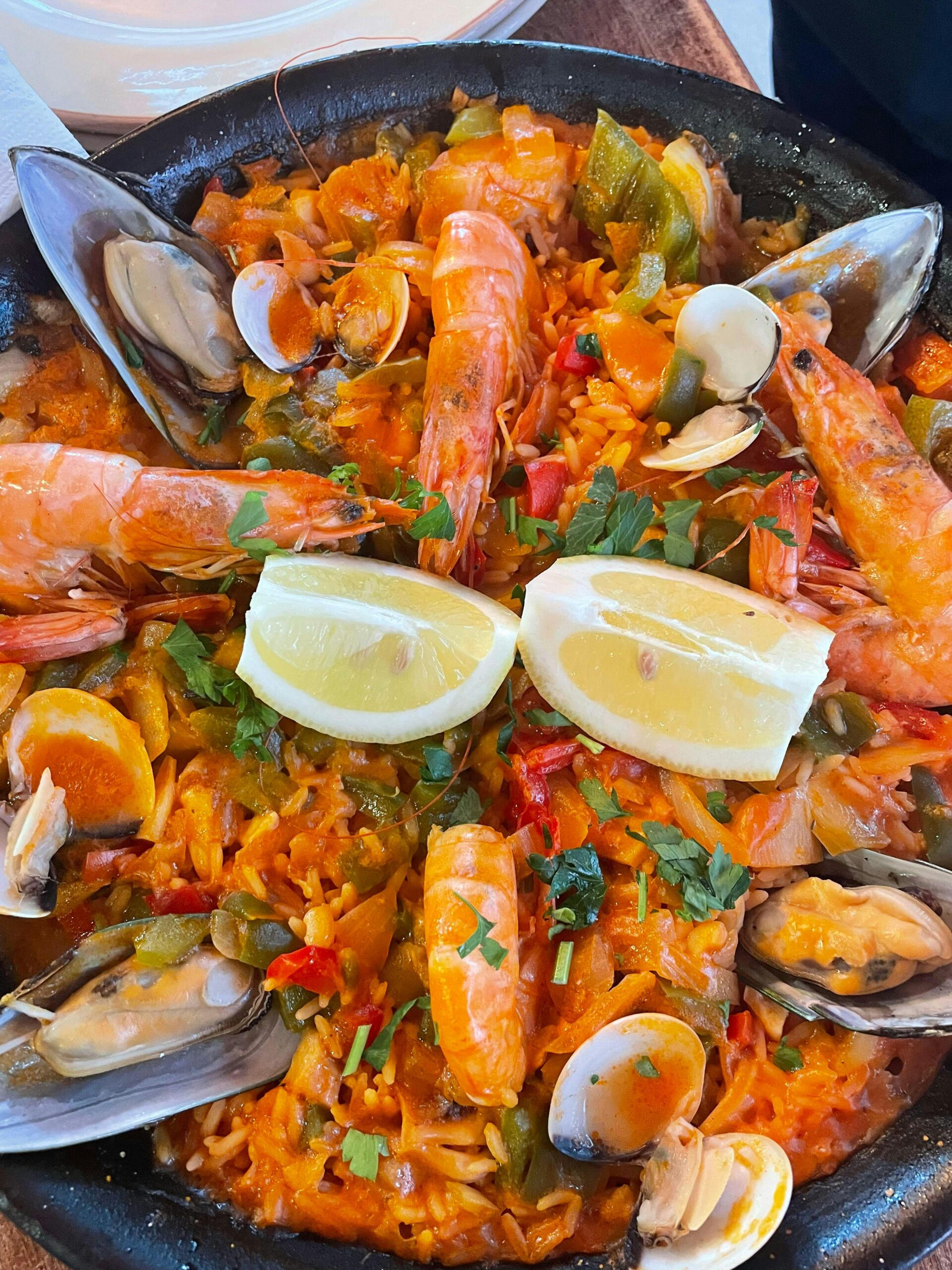 Close-up of traditional Spanish seafood paella with shrimp, mussels, and lemon slices.